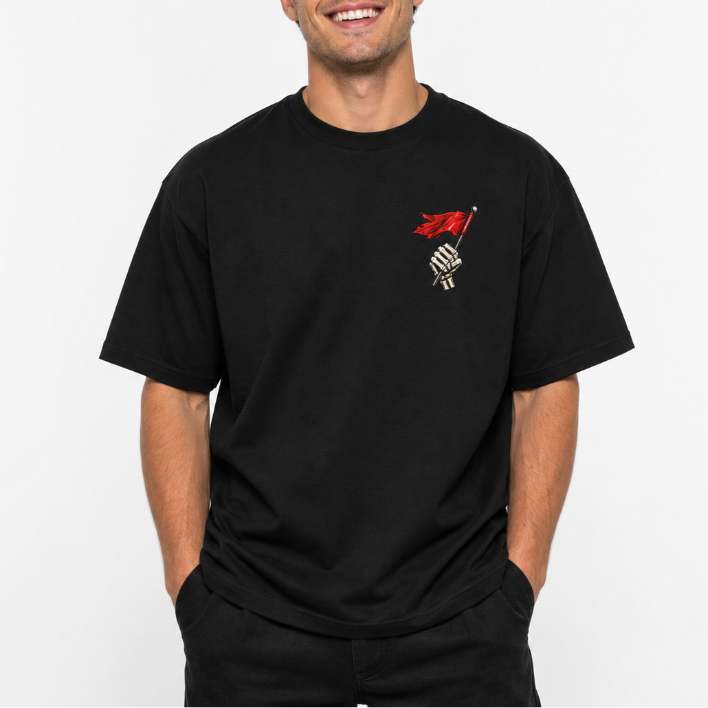 A smiling man wearing a black short-sleeve t-shirt with a small red and white graphic on the left chest, posed against a clean white background.