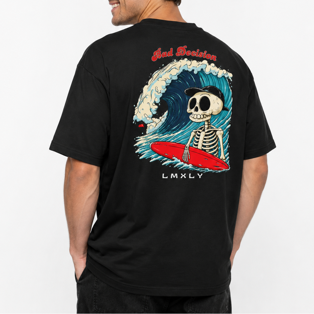 A man wearing a black t-shirt, viewed from the back. The shirt features a large graphic print of a skeleton surfing on a red surfboard inside a blue wave, with 'Bad Decision' written in red above and 'LMXLY' below.