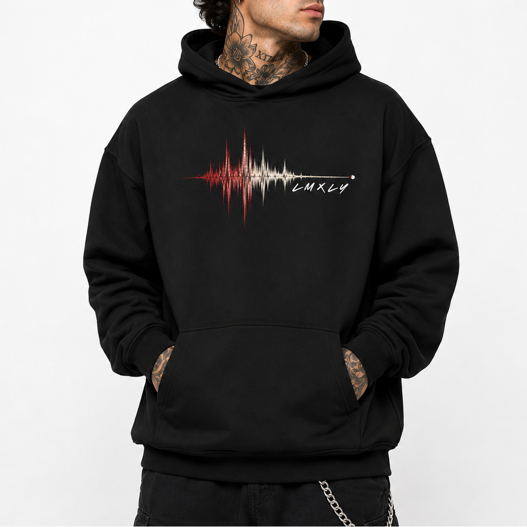 A man wearing a black pullover hoodie with a red and white sound-wave graphic and the word 'LMXLY' printed on the chest, paired with a black baseball cap, against a plain white background.