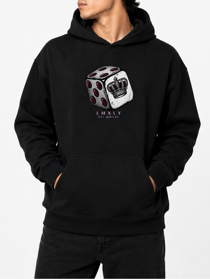A man wearing a black pullover hoodie with a graphic of a white die showing a crown on the front, set against a plain white background.