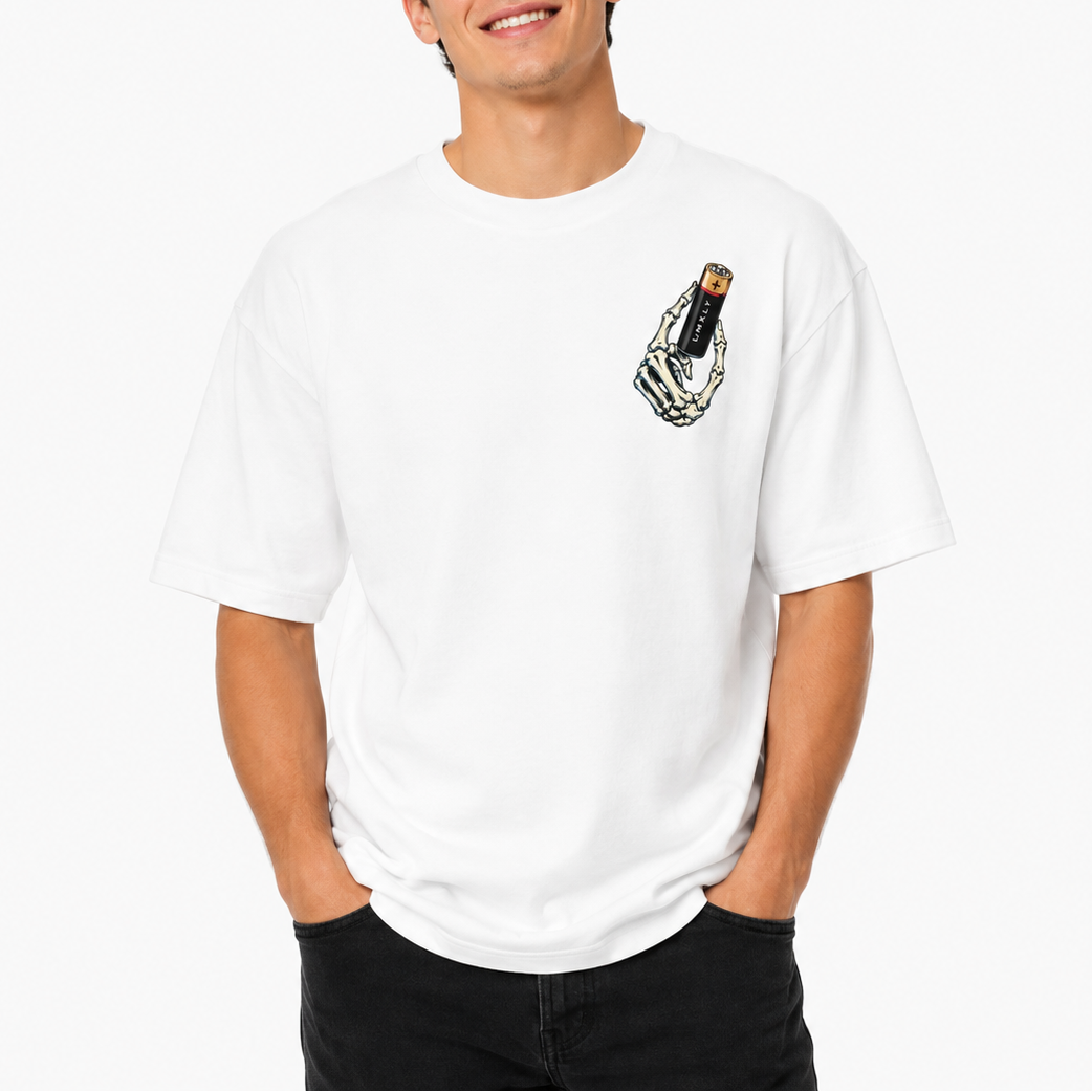 A smiling young man wearing a white crewneck t-shirt with a small graphic of a skeleton hand holding a black and gold vape device on the left chest, paired with black jeans against a clean white background.